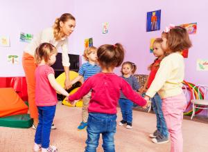 Children with early years provider playing in a circle
