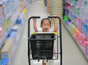 Child pushing grocery cart in aisle. 