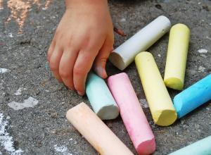 Side walk chalk being picked up by a child.