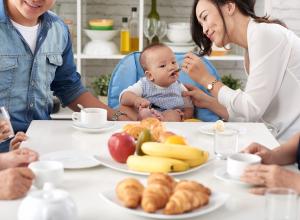 Child eating food with family at dinner table.