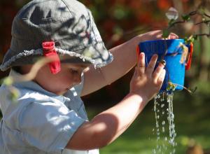 Child playing with bucket full of water.