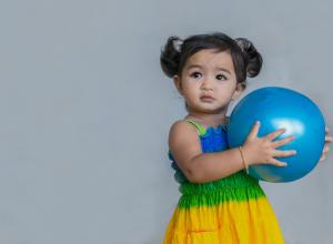 Child with blue ball in her hands.