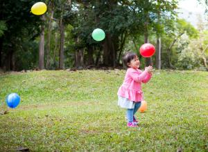 A small child is outside and playing with balloons.