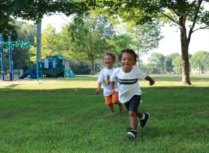 Two children running outside on grass.