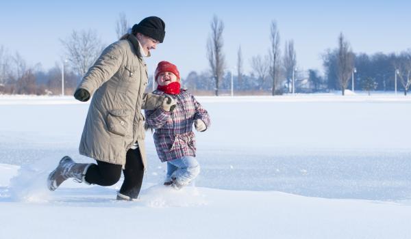 Adult and child running in the snow.