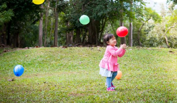 A small child is outside and playing with balloons.