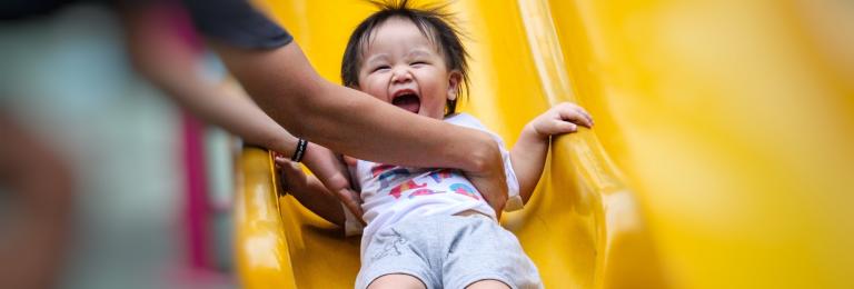 Parent catching smiling child at the end of a slide