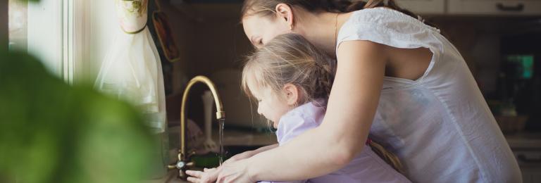 Child washing hands with caregiver.