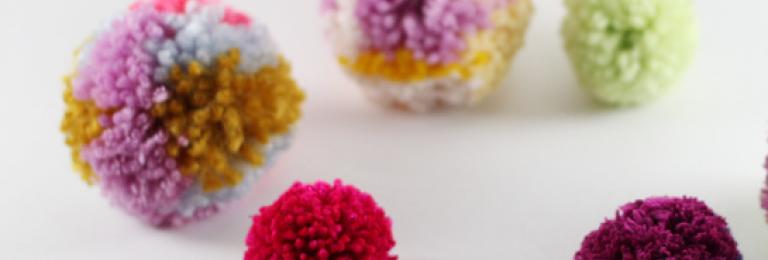 Colourful pom poms  on white surface